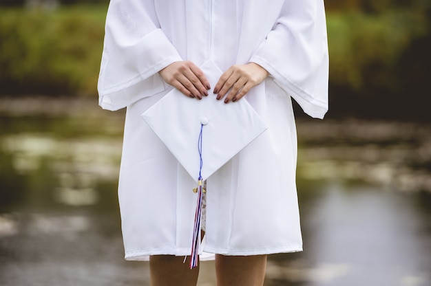 Foto gratuita primer plano de ángulo bajo de una mujer graduada vistiendo una bata y birrete blanco
