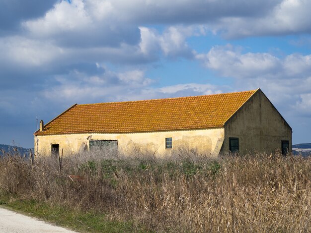 Primer plano de una antigua casa de campo en un campo con nubes blancas y grises en el fondo
