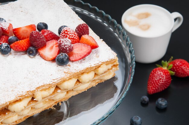 Primer plano de la apetitosa torta de Napoleón con bayas y polvo dulce