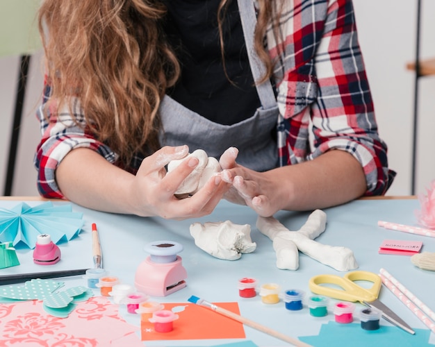 Primer plano de una artista femenina que hace letra con arcilla blanca