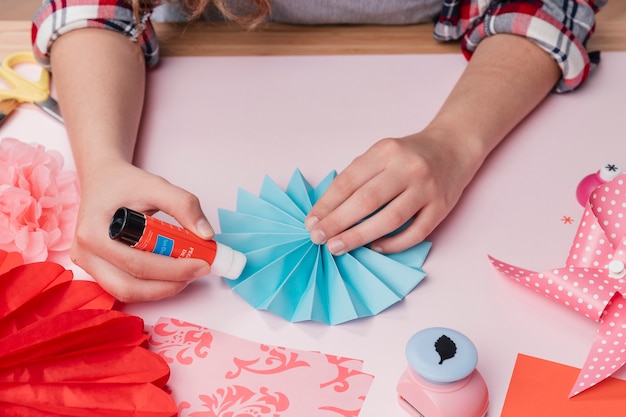 Primer plano de la artista femenina que pega la fan de papel azul de origami