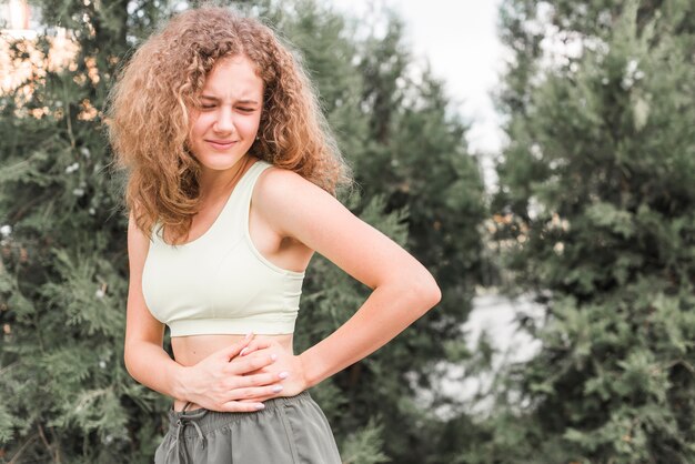 Primer plano de atleta femenina joven que tiene dolor en la cintura