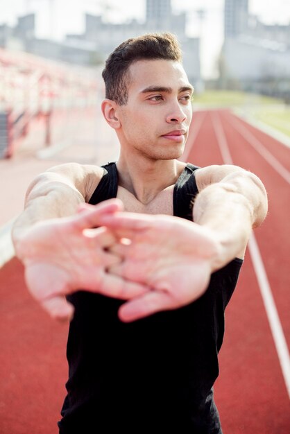 Primer plano de un atleta masculino calentando antes de correr en la pista de atletismo