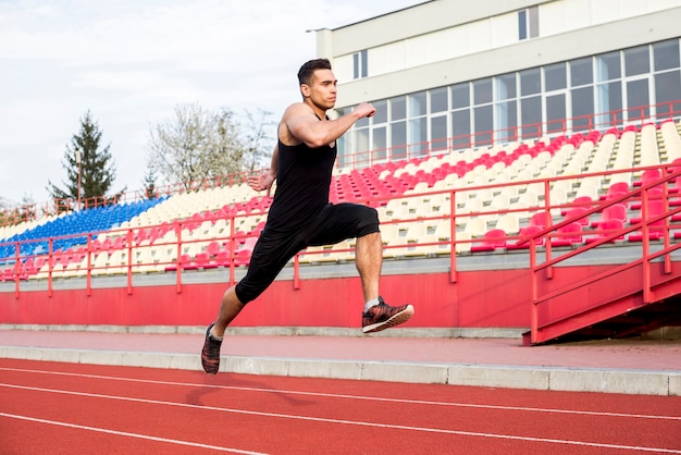 Primer plano de un atleta masculino corriendo en la pista de carreras en el estadio