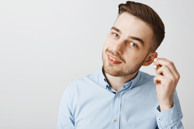 Primer plano del auricular de despegue de joven guapo para escuchar lo que dices