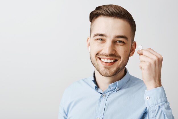 Primer plano del auricular de despegue de joven guapo para escuchar lo que dices