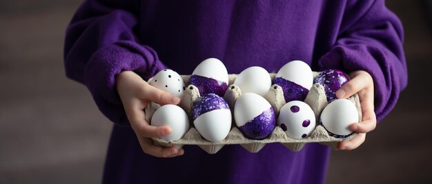 Primer plano de una bandeja de huevos de Pascua púrpura en manos de un niño