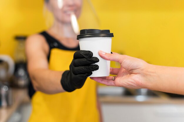 Primer plano de barista que sirve con protección facial