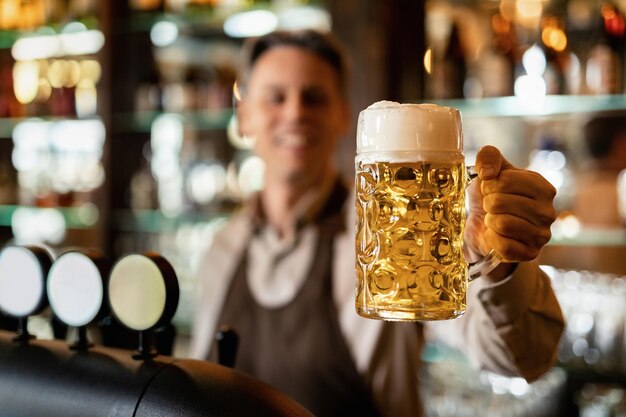 Primer plano de barista sosteniendo un vaso de cerveza artesanal en un bar