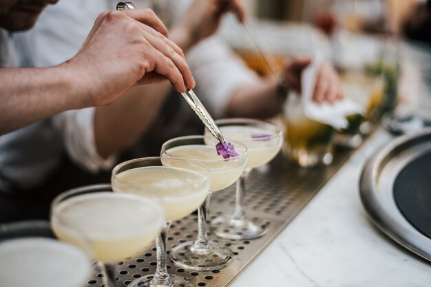 Primer plano de un barman haciendo margaritas con cinco vasos en línea