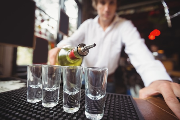 Foto gratuita primer plano de barman vertiendo tequila en vasos de chupito