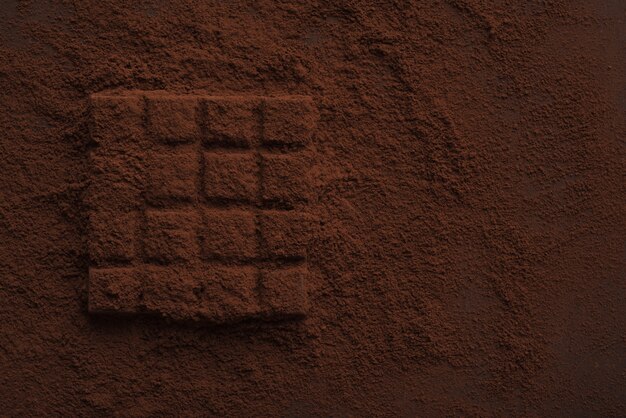 Primer plano de una barra de chocolate negro cubierta de chocolate en polvo