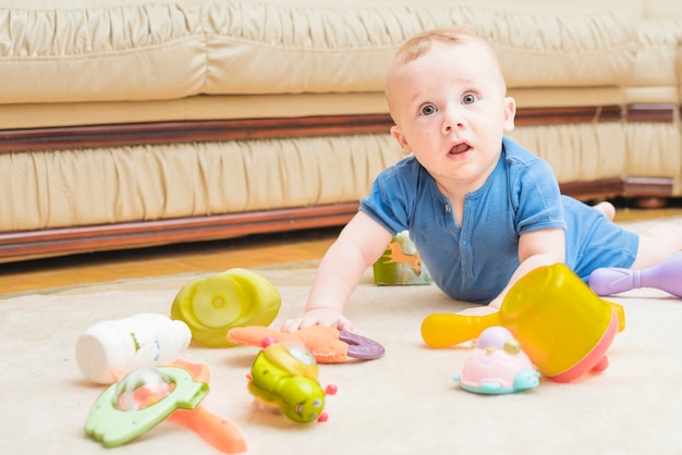 Primer plano de bebé jugando con juguetes coloridos en la alfombra