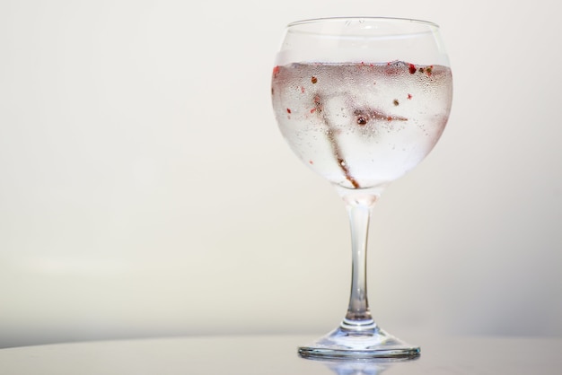 Primer plano de una bebida en un vaso bajo las luces sobre un fondo blanco.