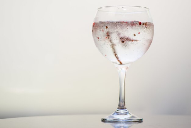 Primer plano de una bebida en un vaso bajo las luces sobre un fondo blanco.