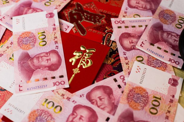 Primer plano de billetes de 100 Yuan chino (CNY) y sobre rojo tradicional chino