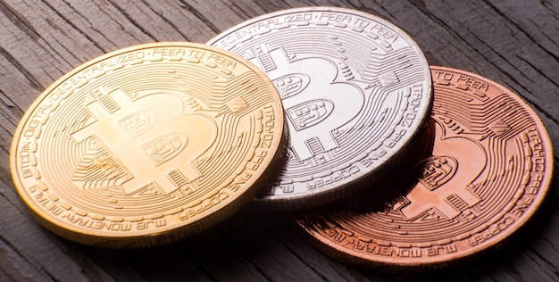 Primer plano de bitcoin de oro, plata y bronce en una superficie de madera