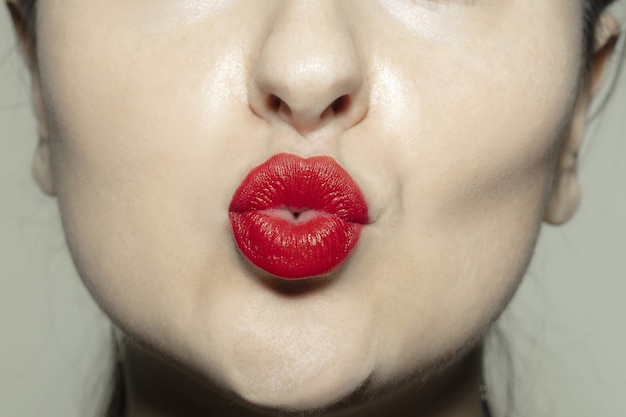 Primer plano boca femenina con labios de brillo rojo brillante