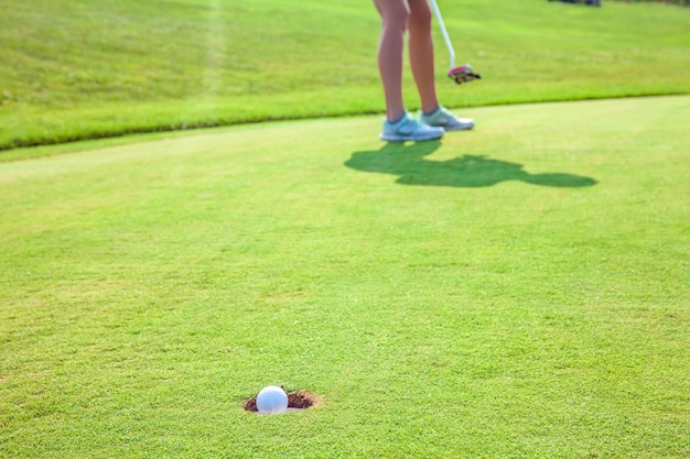 Primer plano de una bola en un hoyo en un campo de golf con un jugador