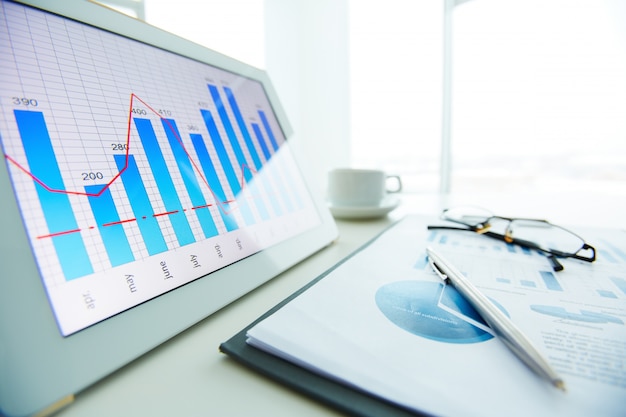 Primer plano de bolígrafo sobre informe económico con la ventana de fondo