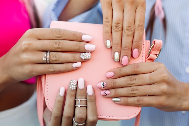 Primer plano de la bolsa con las manos de las chicas con manicura encima.