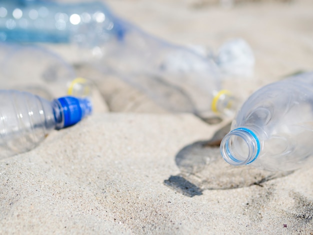 Primer plano de la botella de agua plástica inútil vacía en la arena