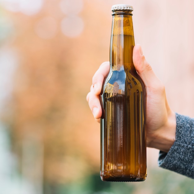 Foto gratuita primer plano de una botella de cerveza en la mano