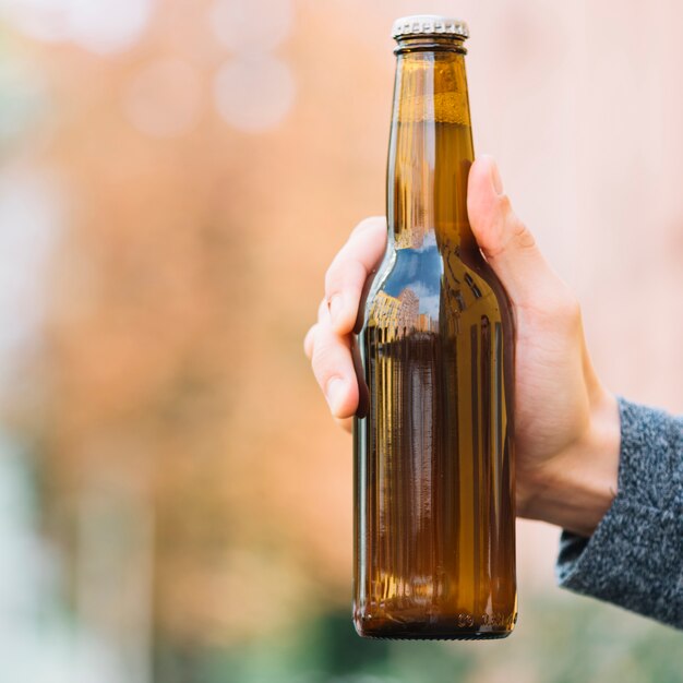 Primer plano de una botella de cerveza en la mano