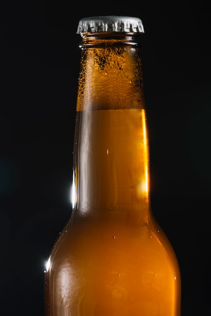 Primer plano de una botella de cerveza sobre fondo negro