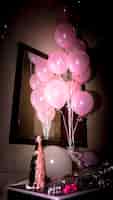 Foto gratuita primer plano de la botella de champán con globos de color rosa en el escritorio