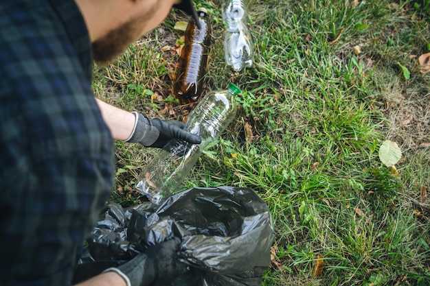 Primer plano de una botella de plástico en una mano masculina limpiando la naturaleza