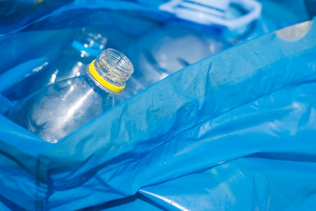 Primer plano de la botella de plástico de residuos en la bolsa de basura azul