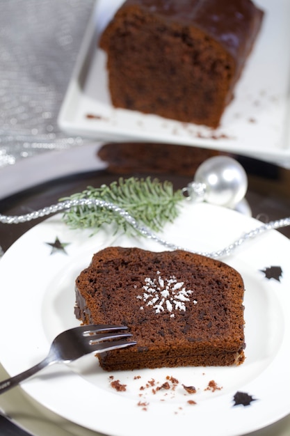 Primer plano de un brownie en una placa blanca junto a la decoración de plata de Navidad