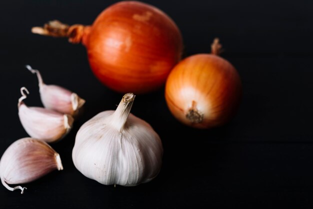 Primer plano de bulbo de ajo y cebollas sobre fondo negro