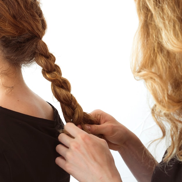 Foto gratuita primer plano del cabello de la hermana de trenzado de mujer sobre fondo blanco