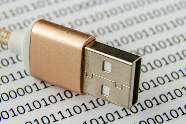 Primer plano de un cable USB en una hoja de papel con números y códigos escritos en él