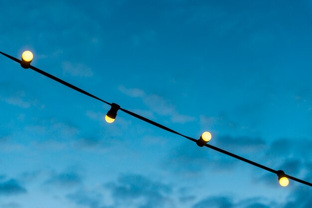 Primer plano de una cadena de luces con cielo azul