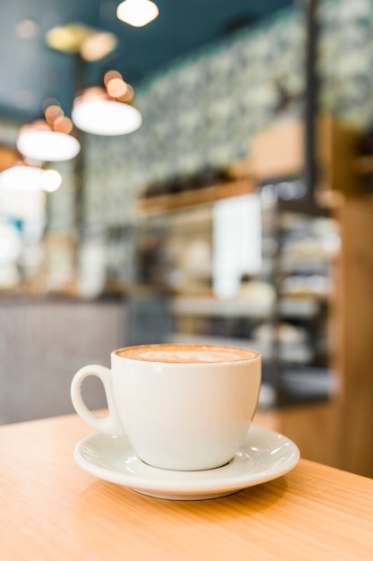 Primer plano de café capuchino con latte de arte en la mesa de madera