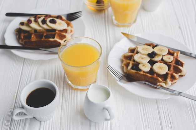 Foto gratuita primer plano de café y jugo cerca de waffles