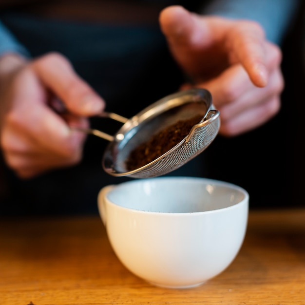 Foto gratuita primer plano de café tamizado en taza por hombre