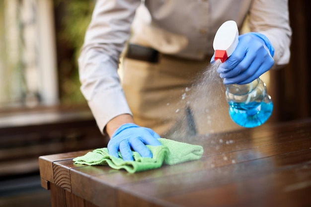 El primer plano de una camarera desinfectando mesas en un café al aire libre