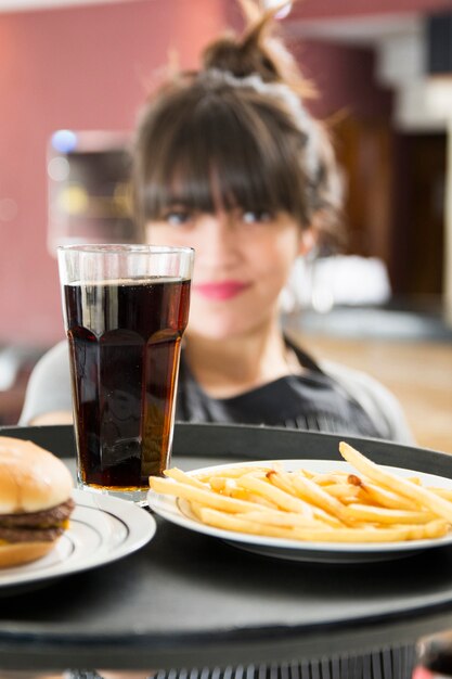 Primer plano, de, camarera femenina, porción, bebidas, con, hamburguesa, y, papas fritas