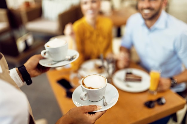 Primer plano de una camarera sirviendo café a una pareja en un café