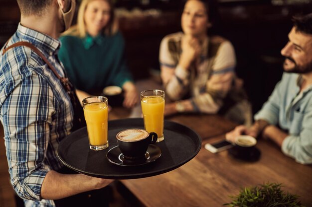 Primer plano de un camarero que sirve bebidas a los clientes en un café