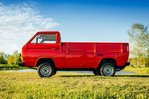 Foto gratuita primer plano de un camión rojo en el campo verde junto al agua