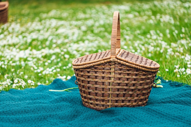 Primer plano de una canasta de picnic sobre un paño azul rodeado de flores blancas