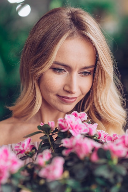 Primer plano de la cara de la mujer mirando flores rosadas