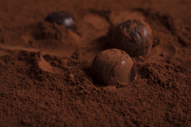 Primer plano de caramelos de chocolate sobre chocolate en polvo