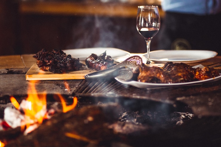 Foto gratuito primer plano de carne a la parrilla y una copa de vino cerca de la chimenea