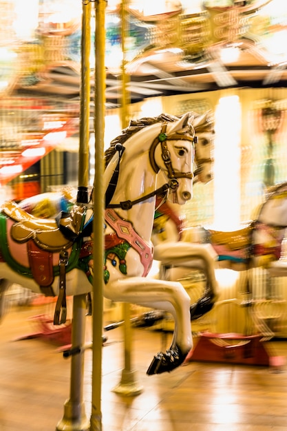 Primer plano de un carrusel de caballos iluminado detalle